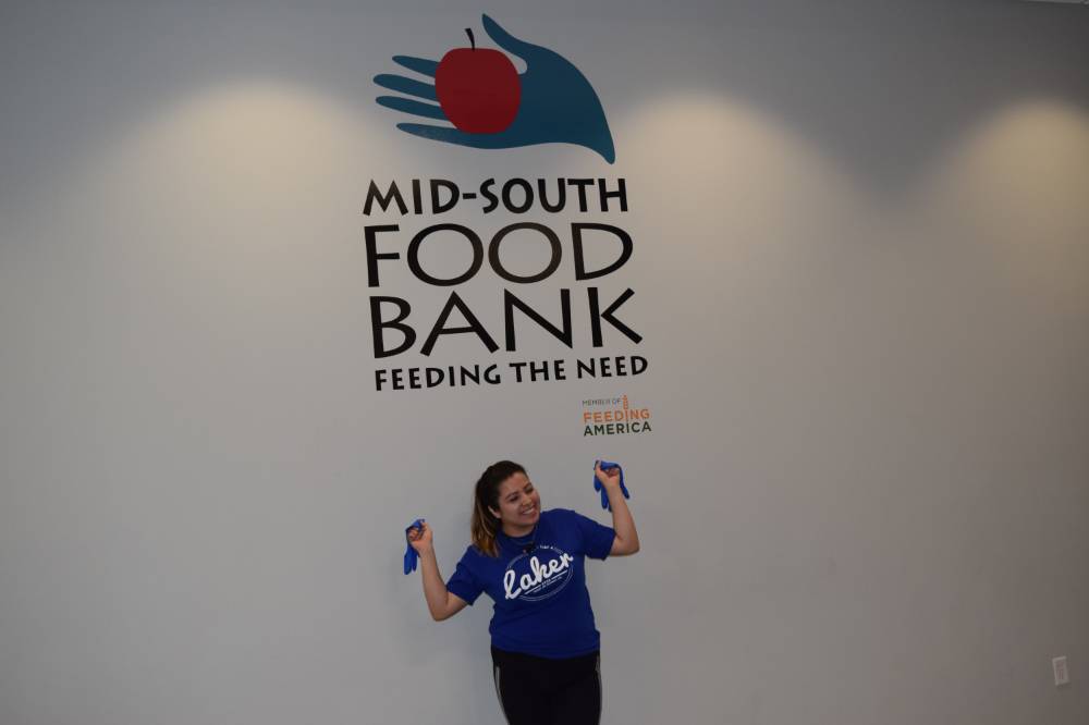 Photo of student posing in front of Food Bank Sign from Service Project